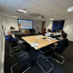 laura speaking at an event in a room with participants seated at tables